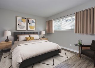 Spacious bed with tufted headboard next to pillows, sheets and duvet and tables on both sides