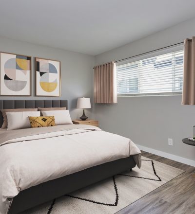 Spacious bed with tufted headboard next to pillows, sheets and duvet and tables on both sides