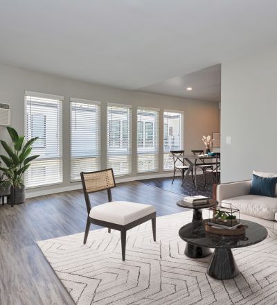 White couch with teal and orange cushions next to a marbled coffee table and a wooden chair with a cushion seat