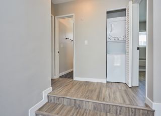 Washer and dryer stacked together in a closet at the top of two stairs.