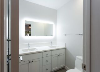 Wide backlit mirror overlooking twin bathroom sinks