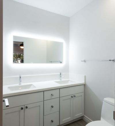 Wide backlit mirror overlooking twin bathroom sinks