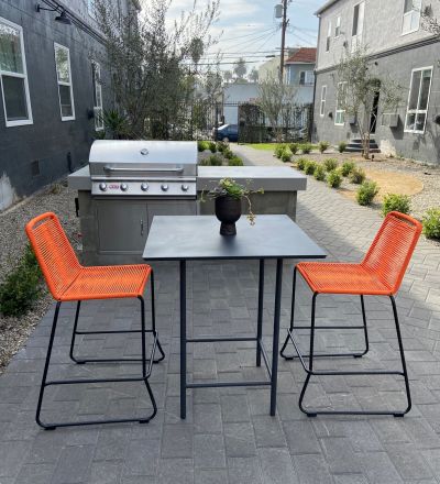 Table and two chairs on a ground level patio with a BBQ