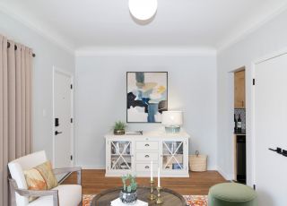 Armchair and ottoman next to the drawer chest dresser with a plant and lamp on top