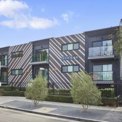 Nash on Normal building front with garden beds and tall trees