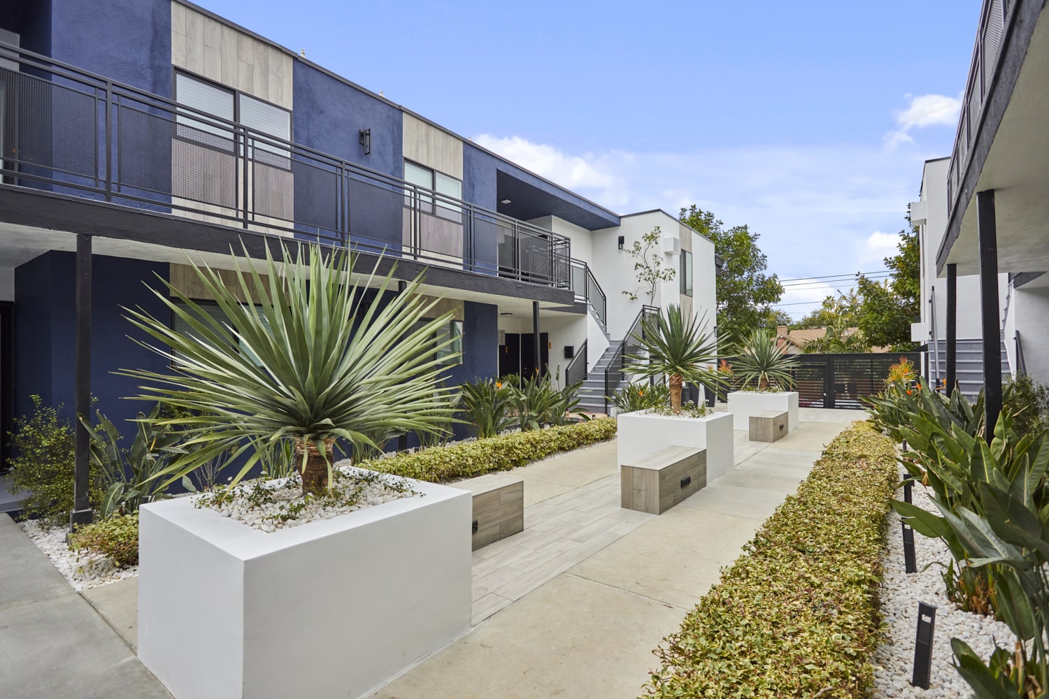 Courtyard area with cement potted plants next to garden beds at Callie on Curson building