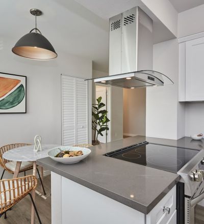 Kitchen counter with electric stovetop under a range hood next to the dining area