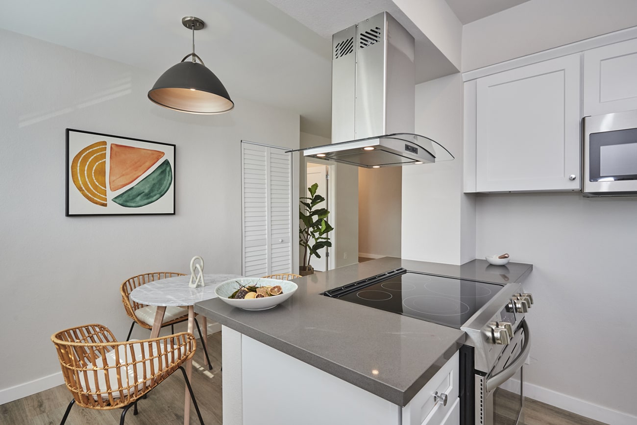 Kitchen counter with electric stovetop under a range hood next to the dining area