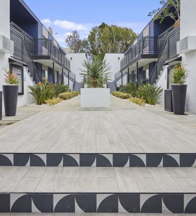 Stairs leading to the apartment courtyard decorated with potted plants on each side and a cement potted plant in the center