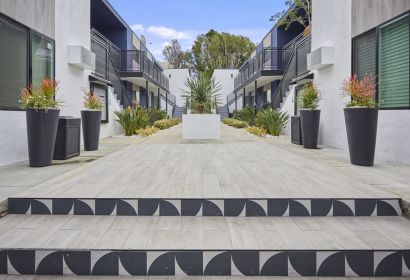 Stairs leading to the apartment courtyard decorated with potted plants on each side and a cement potted plant in the center