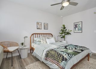 Wooden framed bed with pillows and sheets next to a donut chair at Callie on Curson bedroom