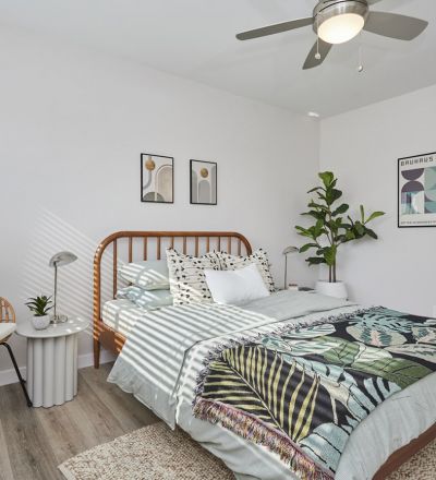 Wooden framed bed with pillows and sheets next to a donut chair at Callie on Curson bedroom
