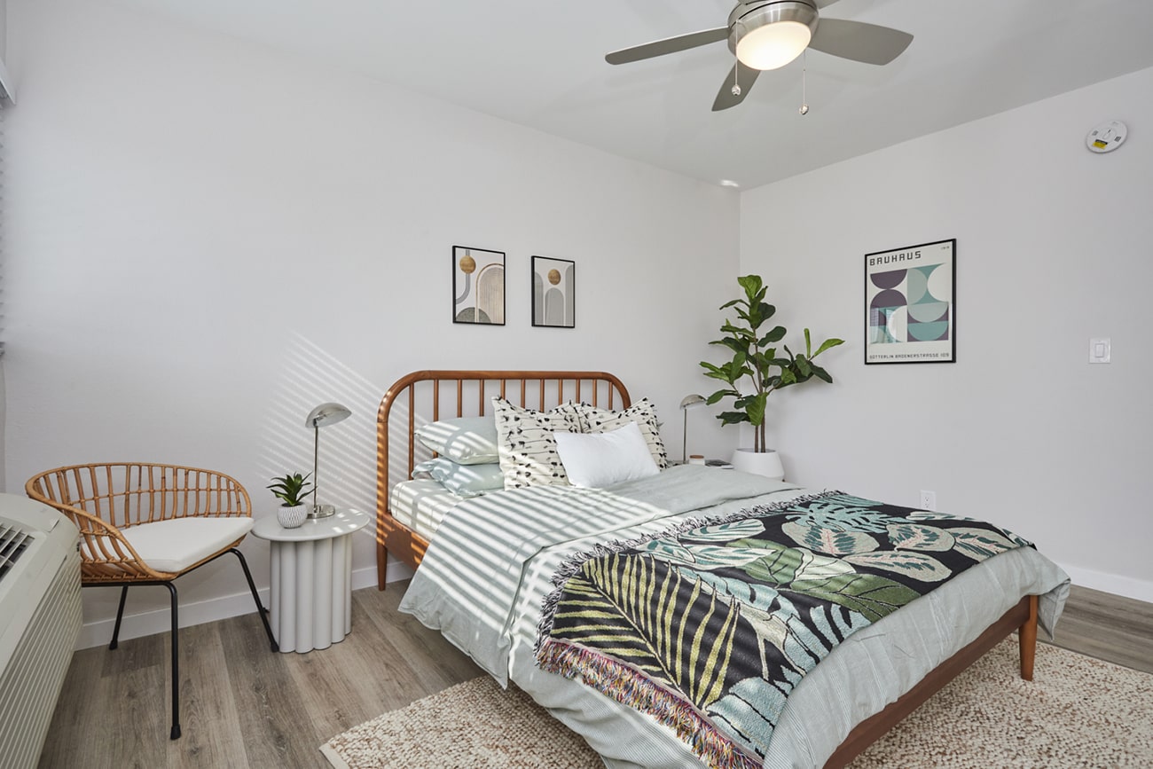 Wooden framed bed with pillows and sheets next to a donut chair at Callie on Curson bedroom