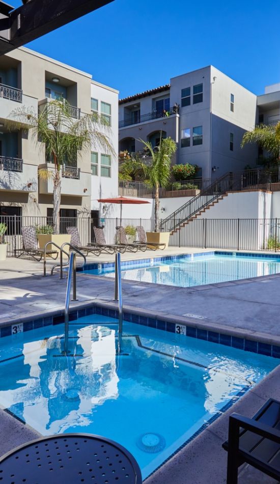 Outdoor pool and hot tub surrounded by lounge chairs at Magnolia apartments