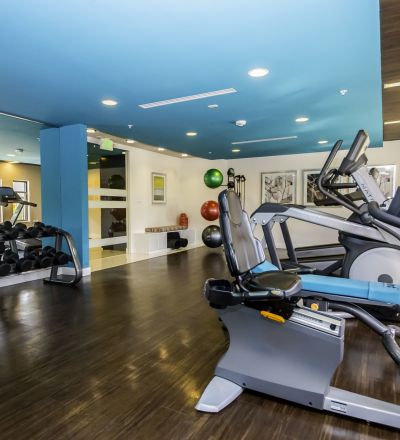 Dumbbells placed on a rack next to exercise equipments at the Park Encino apartment's gym
