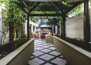 Concrete raised garden beds under a gazebo roof of plants leading to the courtyard area