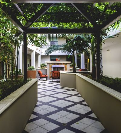 Concrete raised garden beds under a gazebo roof of plants leading to the courtyard area