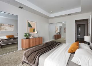 Spacious bed with duvet, sheets and pillows overlooking the dresser and mirror sliding door closets at Park Encino bedroom