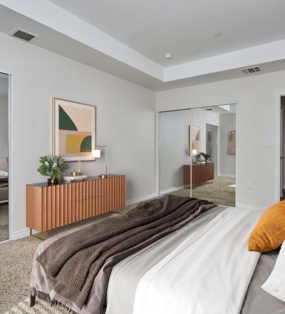 Spacious bed with duvet, sheets and pillows overlooking the dresser and mirror sliding door closets at Park Encino bedroom