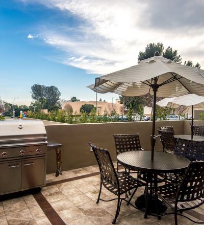 patio table with a stand umbrella next to woven chairs and bbq at Park Encino apartments