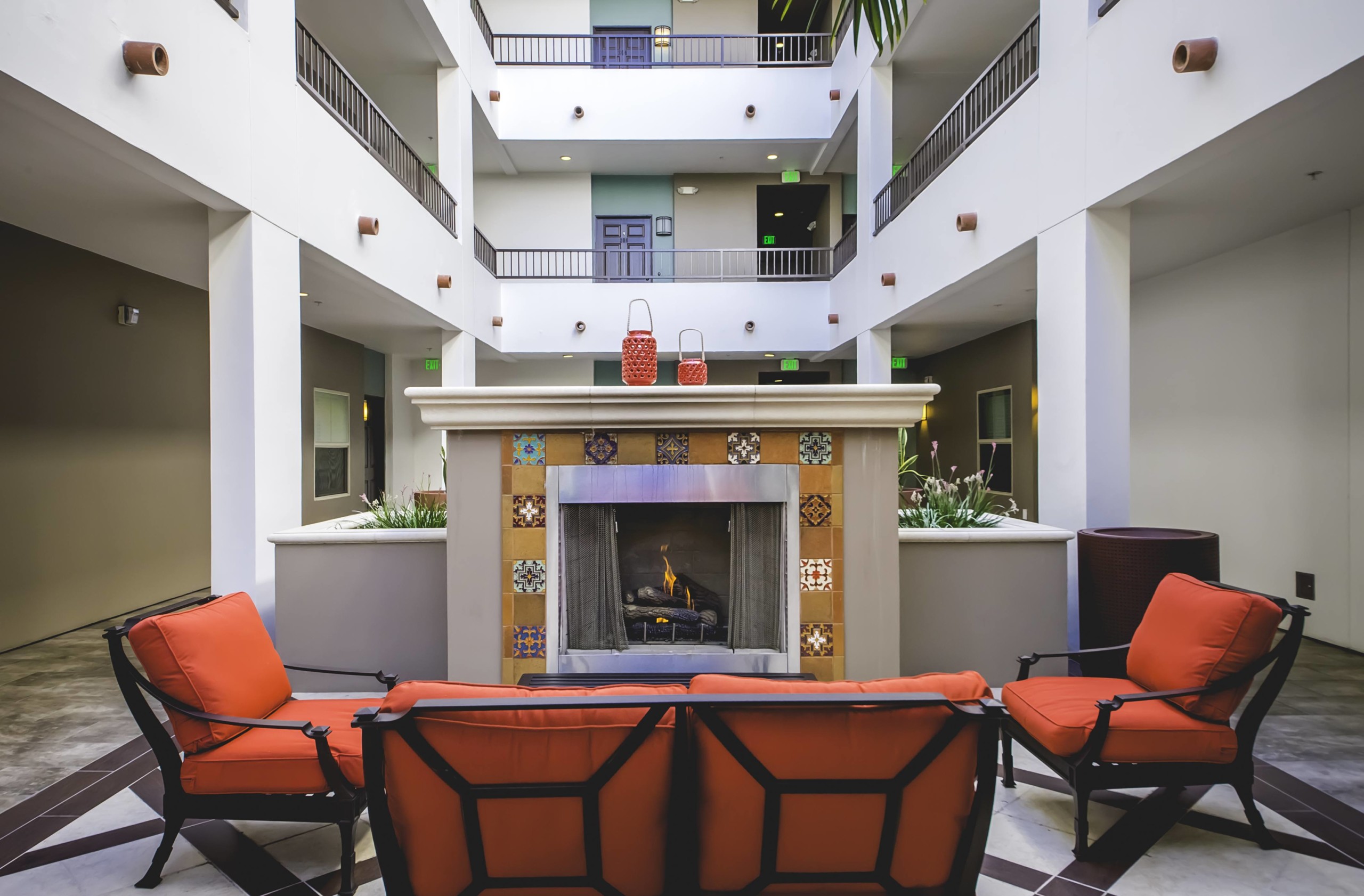 wooden patio chairs with red cushions next to an ornate fireplace at Park Encino's courtyard area