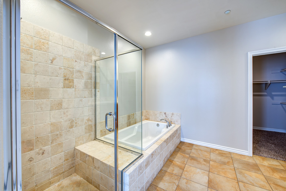 Marbled bathtub next to a glass-enclosed shower stall