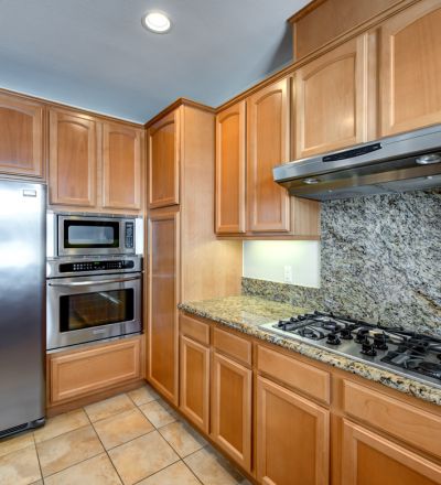 Marble kitchen stove countertop with wooden cabinets and stainless steel kitchen appliances