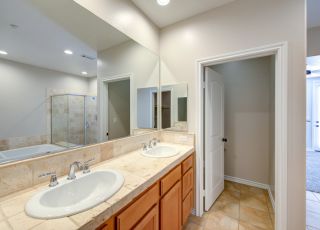 Twin bathroom sink set on a wide countertop next to a large wall mirror