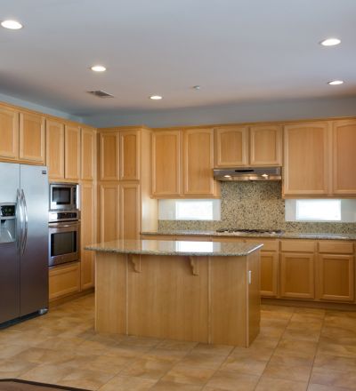Wide kitchen countertop with wooden cabinets next to a double fridge and microwave and oven