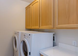 Laundry room with washer and dryer lined together and wooden cabinets on the top