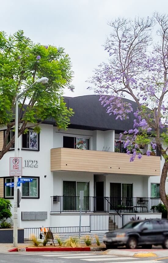 Apartments in West Hollywood; Harper on Hayworth exterior amidst tall trees and Jacaranda tree in the front