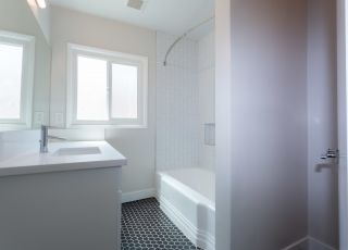White bathroom countertop with white cabinets next to the bathtub at Sage on Sweetzer apartments