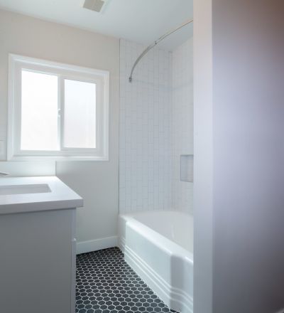 White bathroom countertop with white cabinets next to the bathtub at Sage on Sweetzer apartments