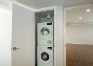 Laundry closet with washer and dryer stacked together at Sage on Sweetzer apartment