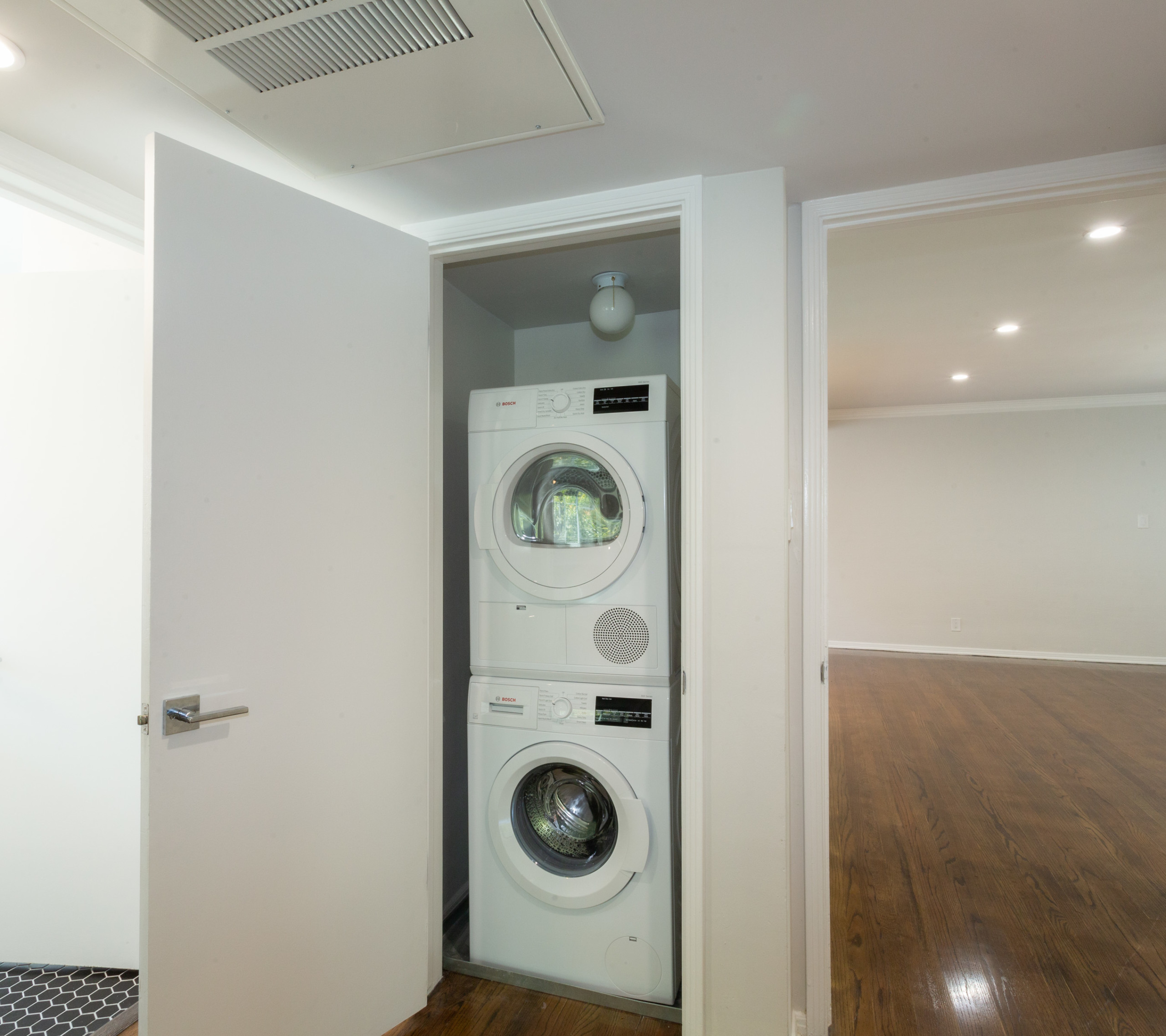 Laundry closet with washer and dryer stacked together at Sage on Sweetzer apartment
