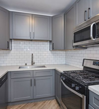 Marble kitchen countertop with grey cabinets including stainless steel microwave and oven