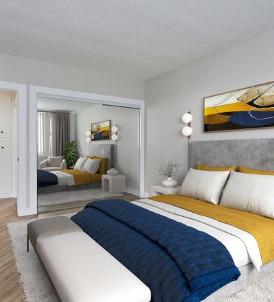 Spacious bed with duvet and pillows and a velvet headboard next to a mirror slider closet and a dresser in the front