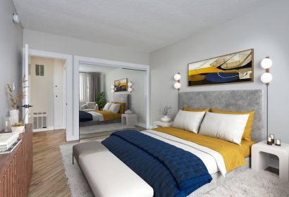 Spacious bed with duvet and pillows and a velvet headboard next to a mirror slider closet and a dresser in the front
