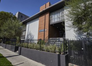 The exterior of Clover on Carlton with potted plants next to the fenced yard surrounding the building