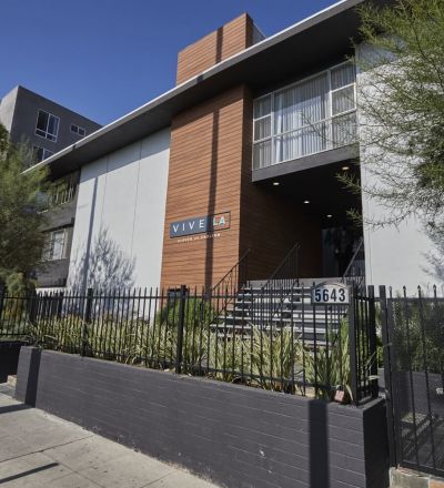 The exterior of Clover on Carlton with potted plants next to the fenced yard surrounding the building