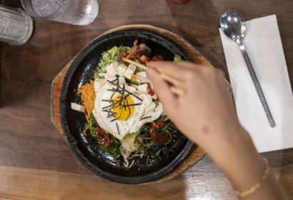 Person eating Korean bibimbap with chopsticks at a Korean restaurant