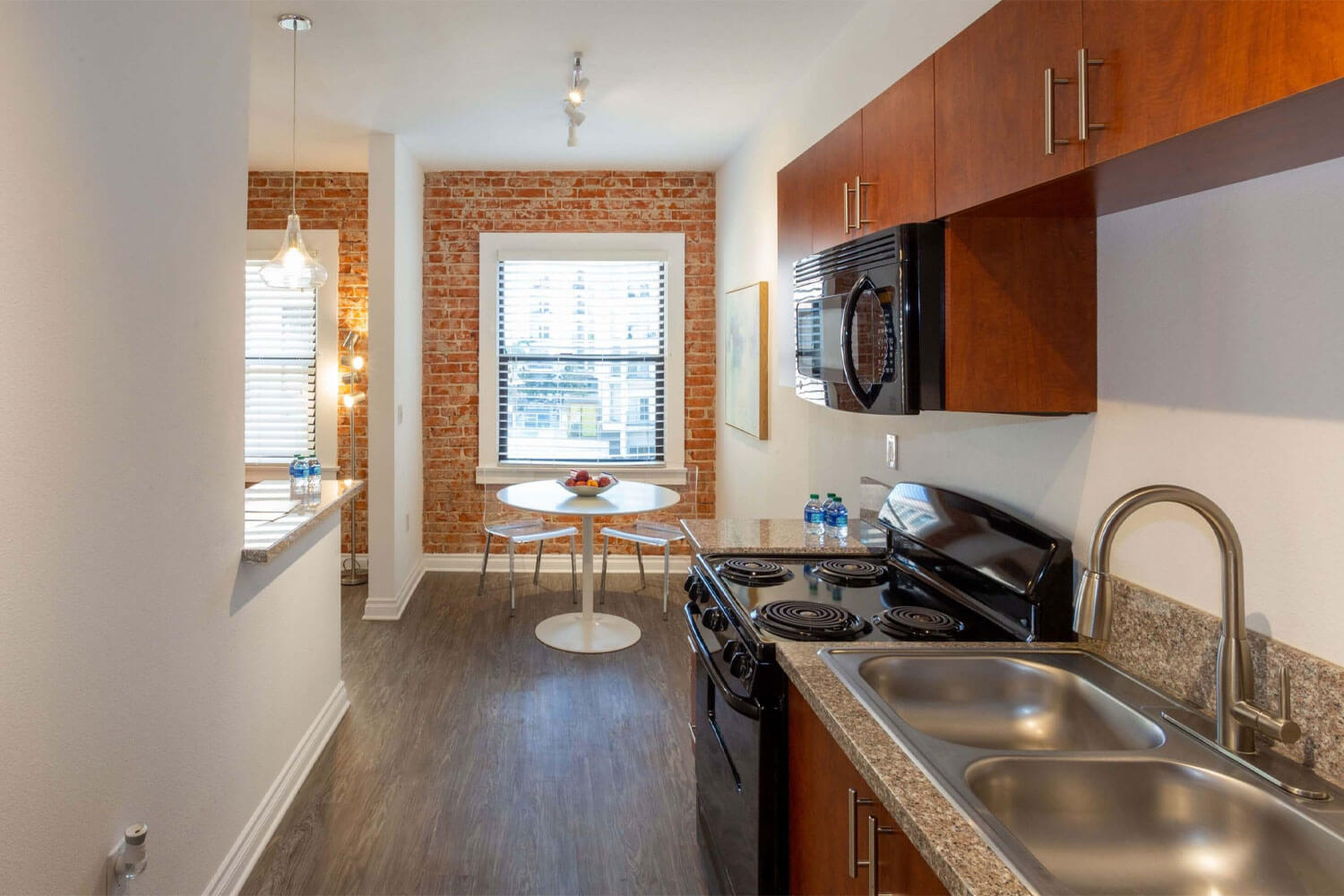 Kitchen sink countertop next to cooktop oven with wooden cabinets beside the dining space; Luxury Hollywood Rentals; boutique community apartments in Hollywood