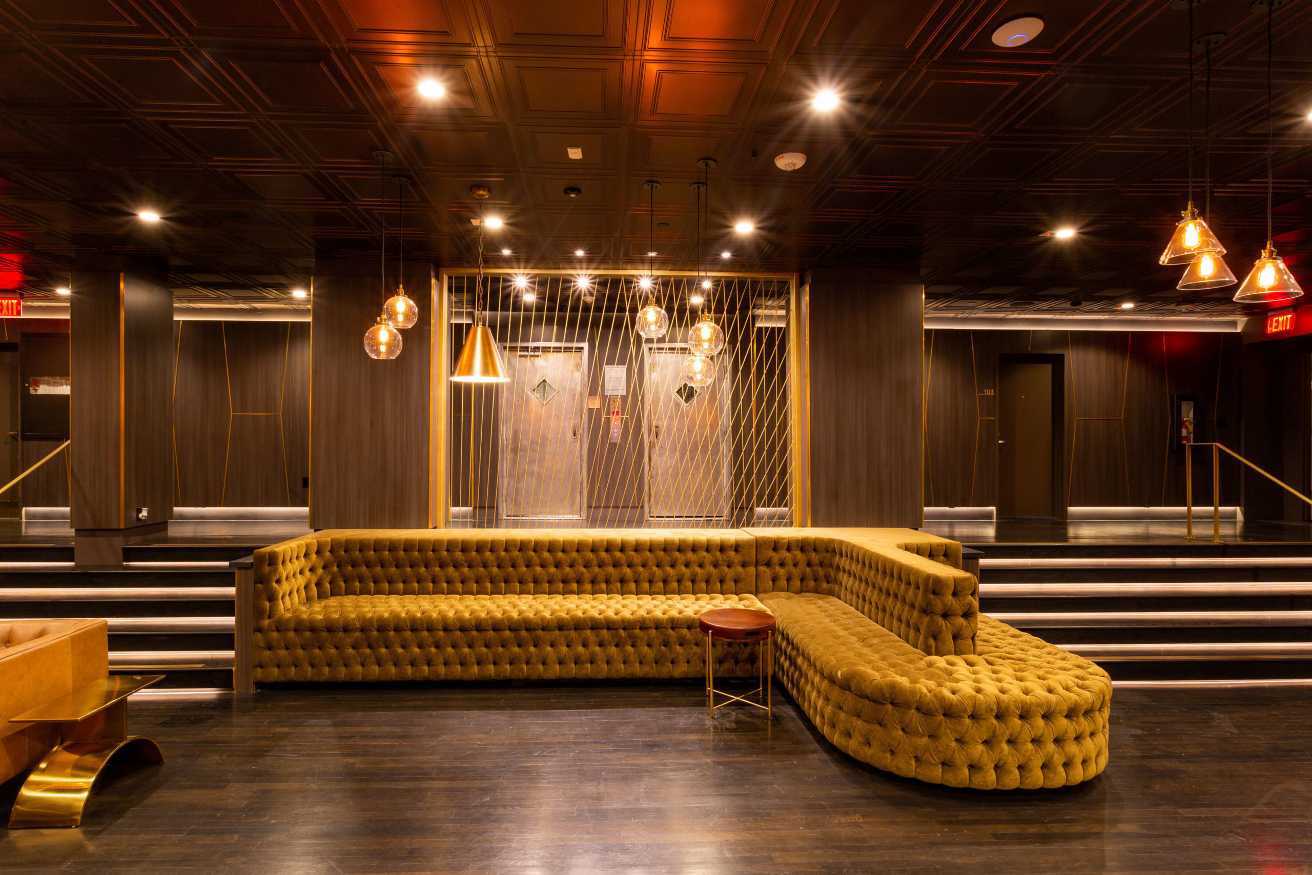 Large tufted sofa next to a wooden tool in The Gershwin Apartments lobby area
