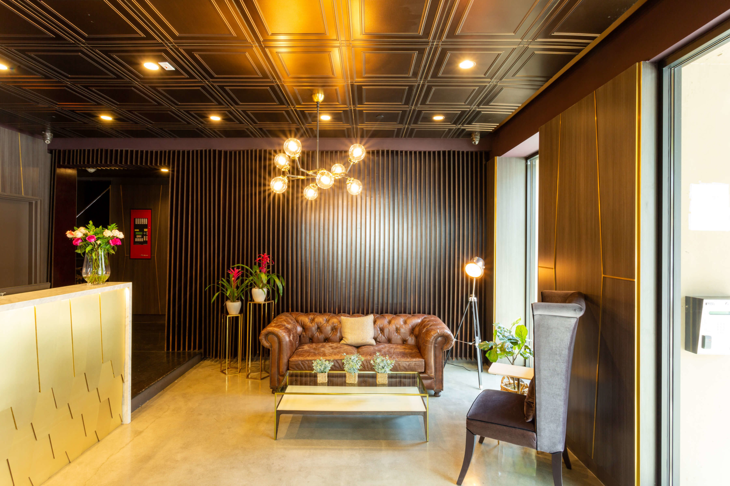 Leather tufted couch next to a coffee table and armchair at The Gershwin Apartments Brick's lobby area