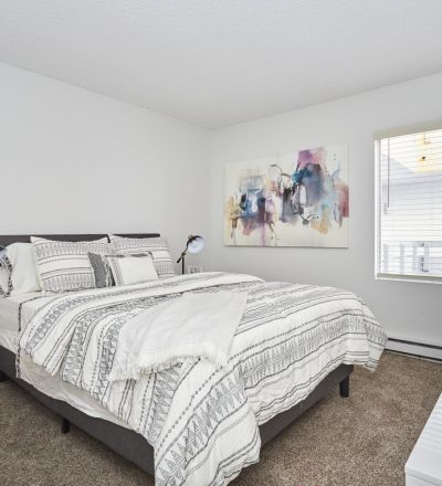 Spacious beds with sheets and pillows next to the dresser and bedside table; Violet on Virgil Apartments