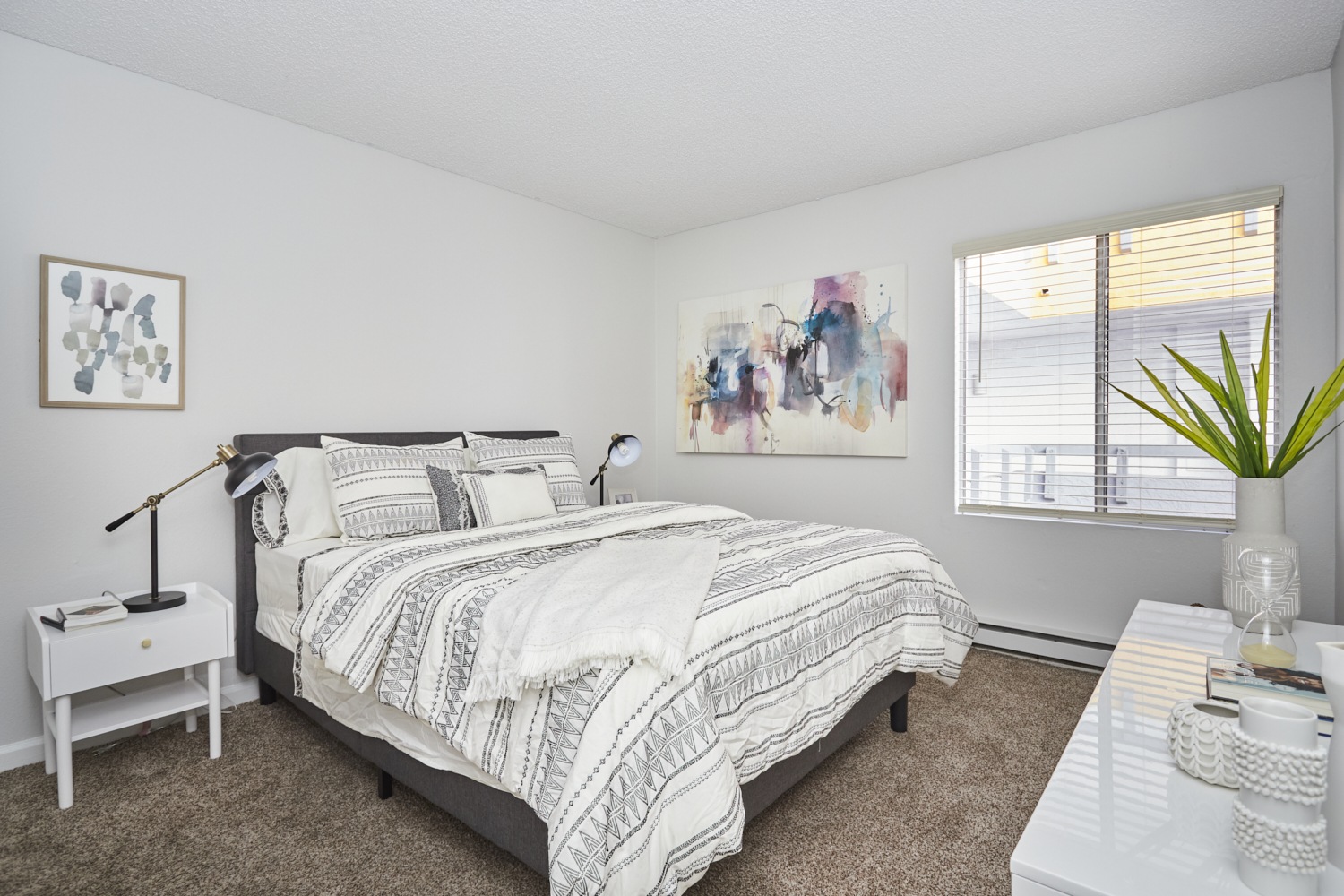 Spacious beds with sheets and pillows next to the dresser and bedside table; Violet on Virgil Apartments