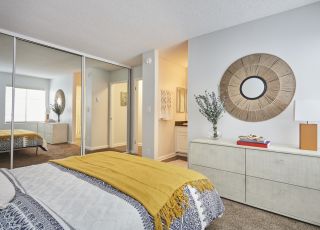 Violet on Virgil Apartments room; Bed overlooking the dresser with a mirror slider closer door on the side