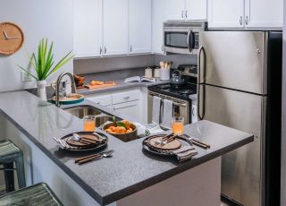 Violet on Virgil; Kitchen countertop with dinner plate setup next to drinks and a bowl of oranges on the kitchen sink