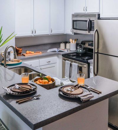 Violet on Virgil; Kitchen countertop with dinner plate setup next to drinks and a bowl of oranges on the kitchen sink