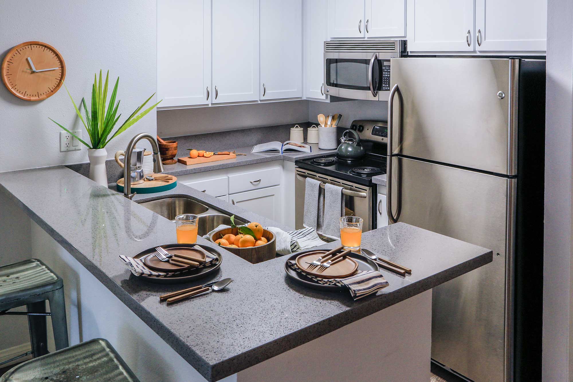 Violet on Virgil; Kitchen countertop with dinner plate setup next to drinks and a bowl of oranges on the kitchen sink